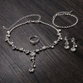 Silver jewelry set with necklace, bracelet, ring, and earrings on a dark wooden surface