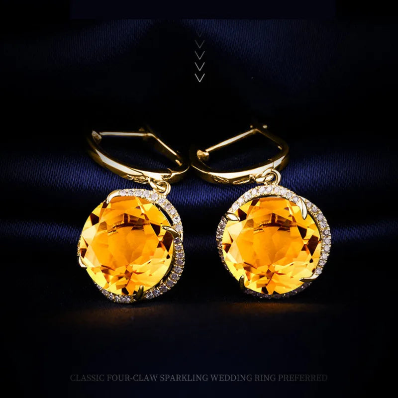 Gold earrings with large orange gemstones on a dark background