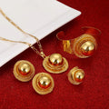 Gold jewelry set including necklace, earrings, and bracelet on a red surface.
