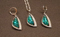 Set of green teardrop jewelry on a brown textured background