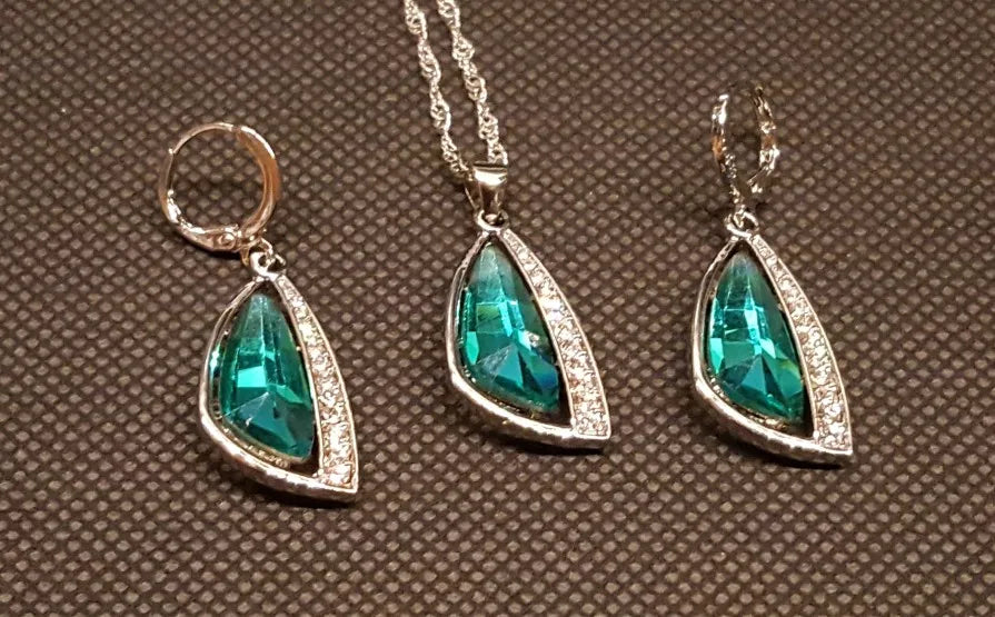 Set of green teardrop jewelry on a brown textured background