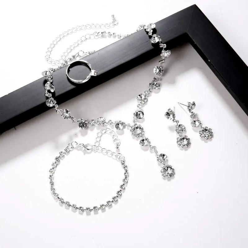 Silver jewelry set with necklace, earrings, ring, and bracelet on a dark background