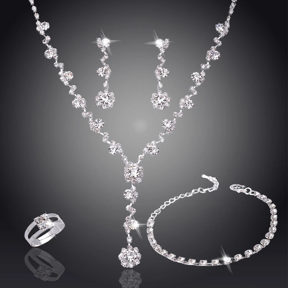 Silver jewelry set with necklace, earrings, ring, and bracelet on a dark background