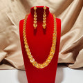 Gold necklace and earrings on a red stand with a beige fabric background