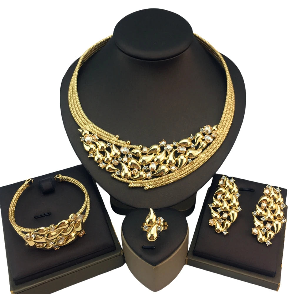 Gold jewelry set including necklace, bracelet, and earrings on black stands.