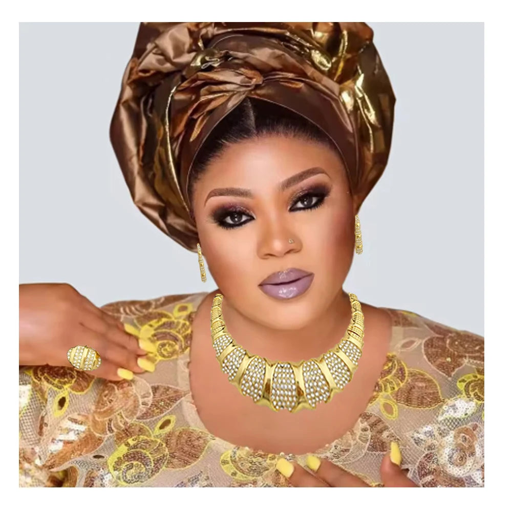 Woman wearing a gold headwrap and jewelry against a light gray background