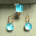 Pair of earrings with blue gemstones on a light green background