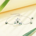 Silver bracelet with green gemstones on a light background