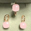 Pair of pink square earrings with gold rims on a light green background