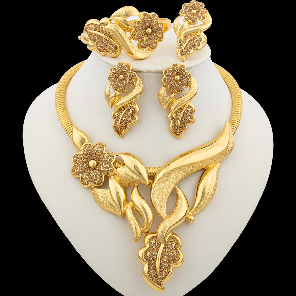 Gold necklace and earrings set on a white stand with a black background
