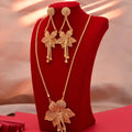 Gold necklace and earrings set on a red stand with a soft pink background