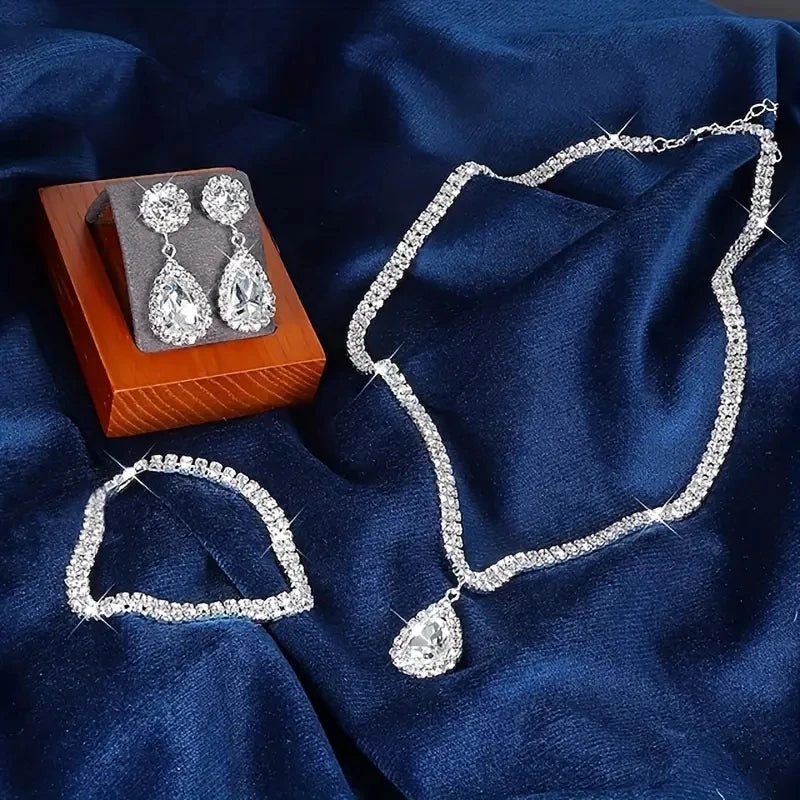 Silver jewelry set including necklace and earrings on a blue fabric background