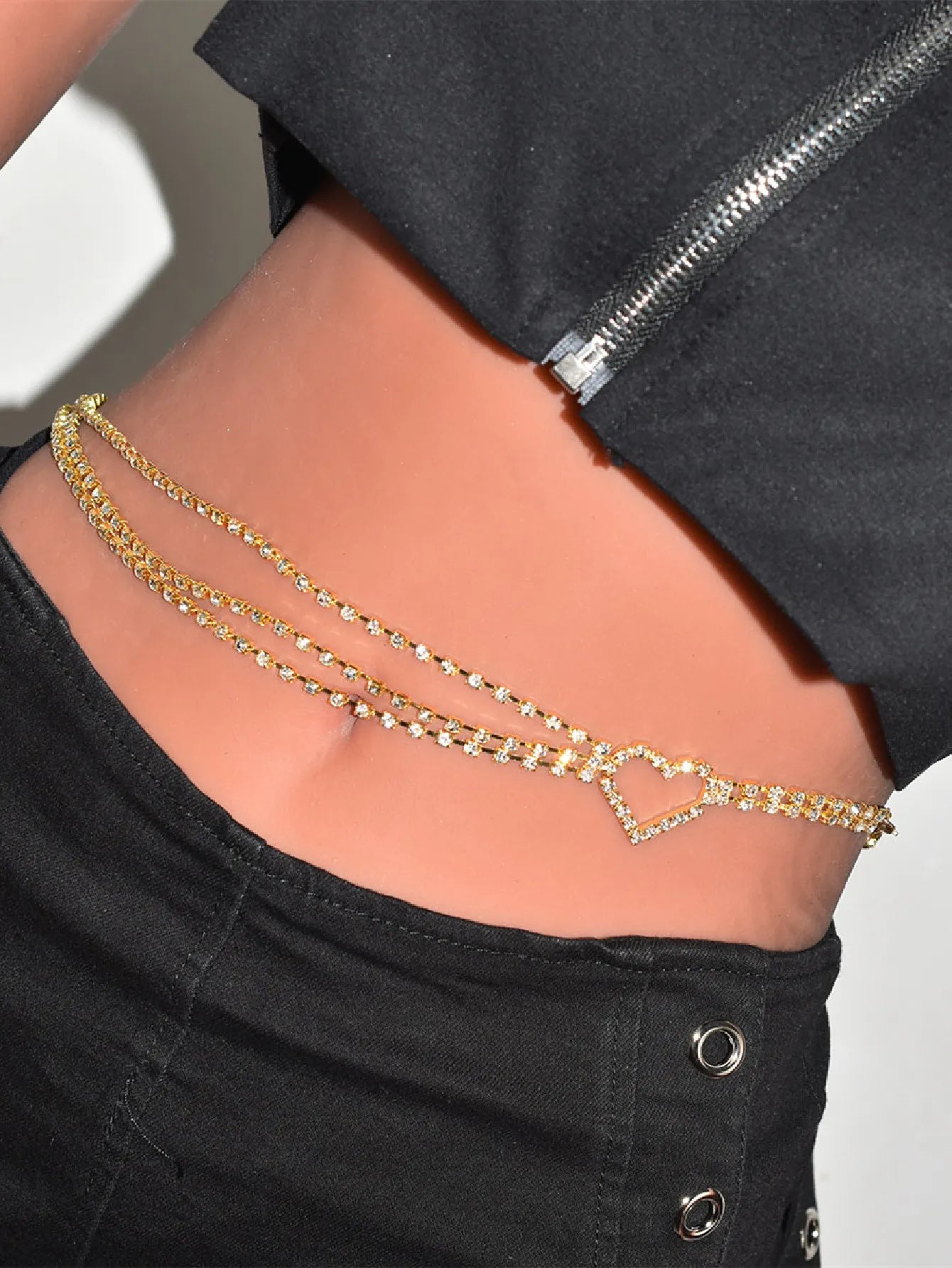 Gold chain belt with heart detail worn by a person against a neutral background