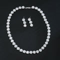 Silver necklace and earrings set on a black background