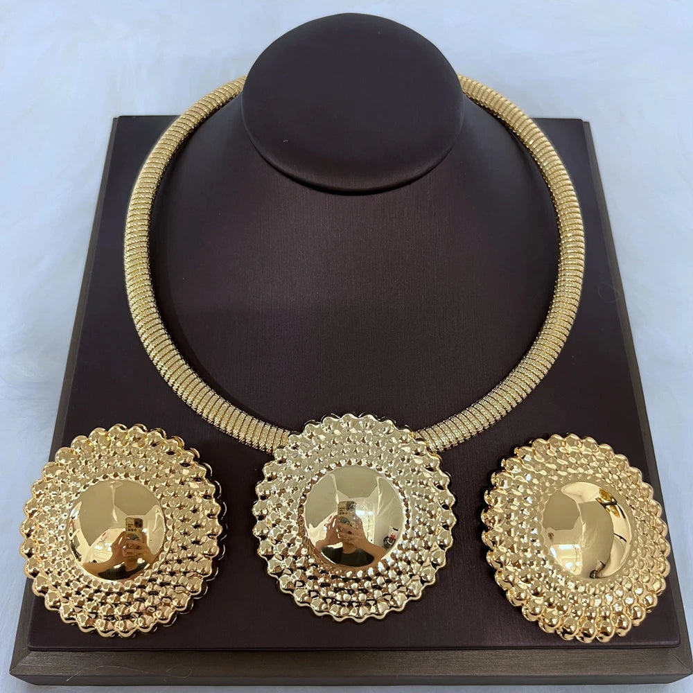 Gold necklace and earrings set on a dark brown stand with a light blue background