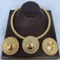 Gold necklace and earrings set on a dark brown stand with a light blue background
