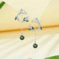 Silver earrings with green gemstones on a yellow background