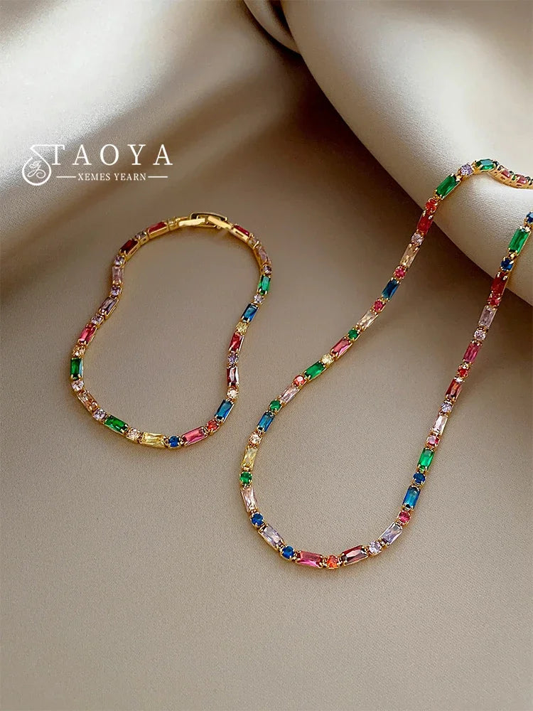 Colorful gemstone necklace and bracelet set on a beige surface with 'TAOYA' branding.