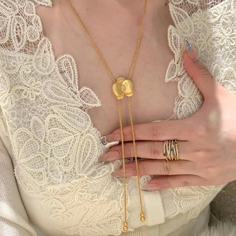 Two necklaces with floral pendants on a beige surface