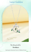Silver necklace with a moon pendant and green stones on a beige background