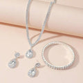 Silver jewelry set with necklace, earrings, and bracelet on a light pink background