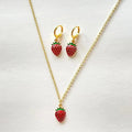 Strawberry-themed necklace and earrings on a white background