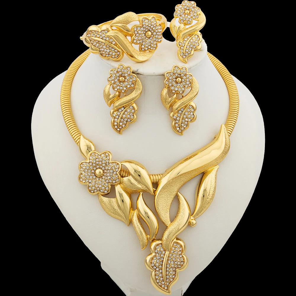 Gold necklace and earrings set on a white stand with a black background
