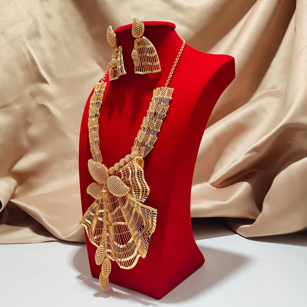 Gold necklace and earrings set on a red stand with a beige fabric background