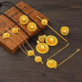 Gold jewelry set including necklace, earrings, and pins on a wooden surface