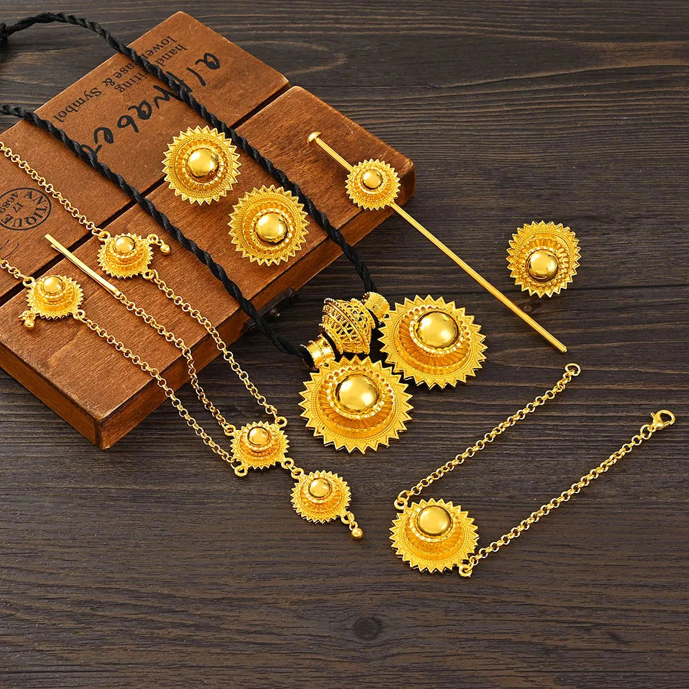 Gold jewelry set including necklace, earrings, and pins on a wooden surface