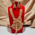 Gold necklace and earrings set on a red stand with a beige fabric background