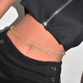 Gold chain necklace worn by a person with black pants and a white background