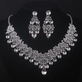 Silver necklace and earrings set on a black background