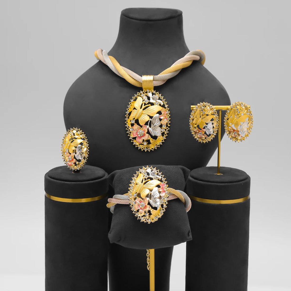 Jewelry set including earrings, necklace, and bracelet on a neutral background