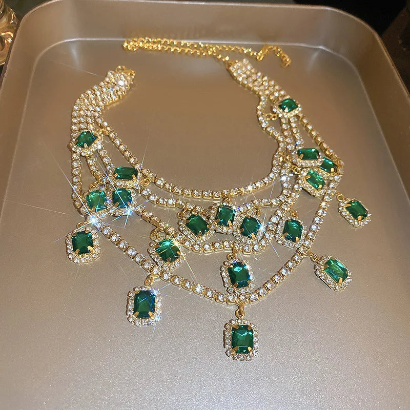 Gold necklace with green gemstones on a metallic surface