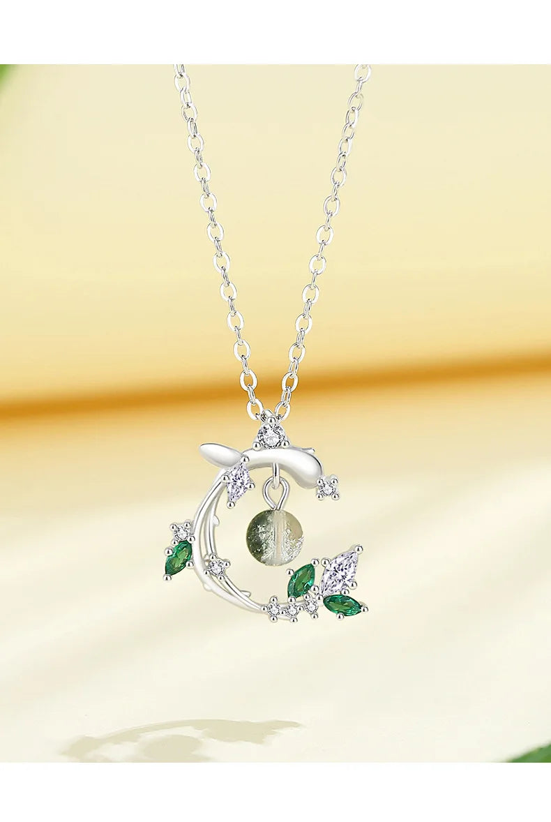 Silver necklace with green gemstones on a yellow background
