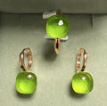 Green gemstone earrings with rose gold accents on a light gray background