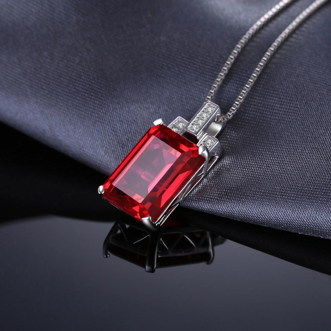 Red gemstone pendant with silver chain on a white background, featuring Jewelry Palace branding.