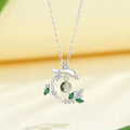 Silver necklace with green gemstone pendant on a yellow background