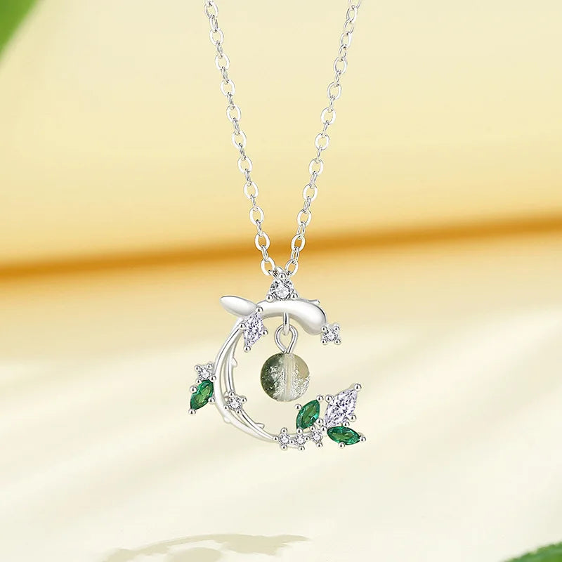 Silver necklace with green gemstone pendant on a yellow background