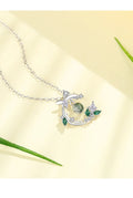 Silver necklace with green gemstones on a light yellow background