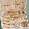 Jewelry organizer with gold and pearl necklaces, earrings, and rings.