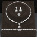 Silver jewelry set including necklace, earrings, and ring on a brown cushion