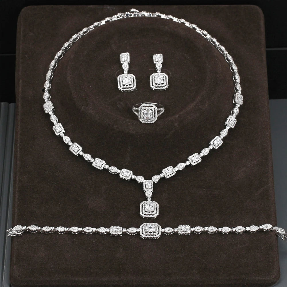 Silver jewelry set including necklace, earrings, and ring on a brown cushion