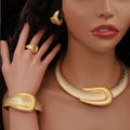Close-up of a mannequin wearing gold jewelry including a necklace, bracelet, and earrings.