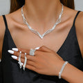 Silver jewelry set including necklace, earrings, and bracelet on a model against a neutral background