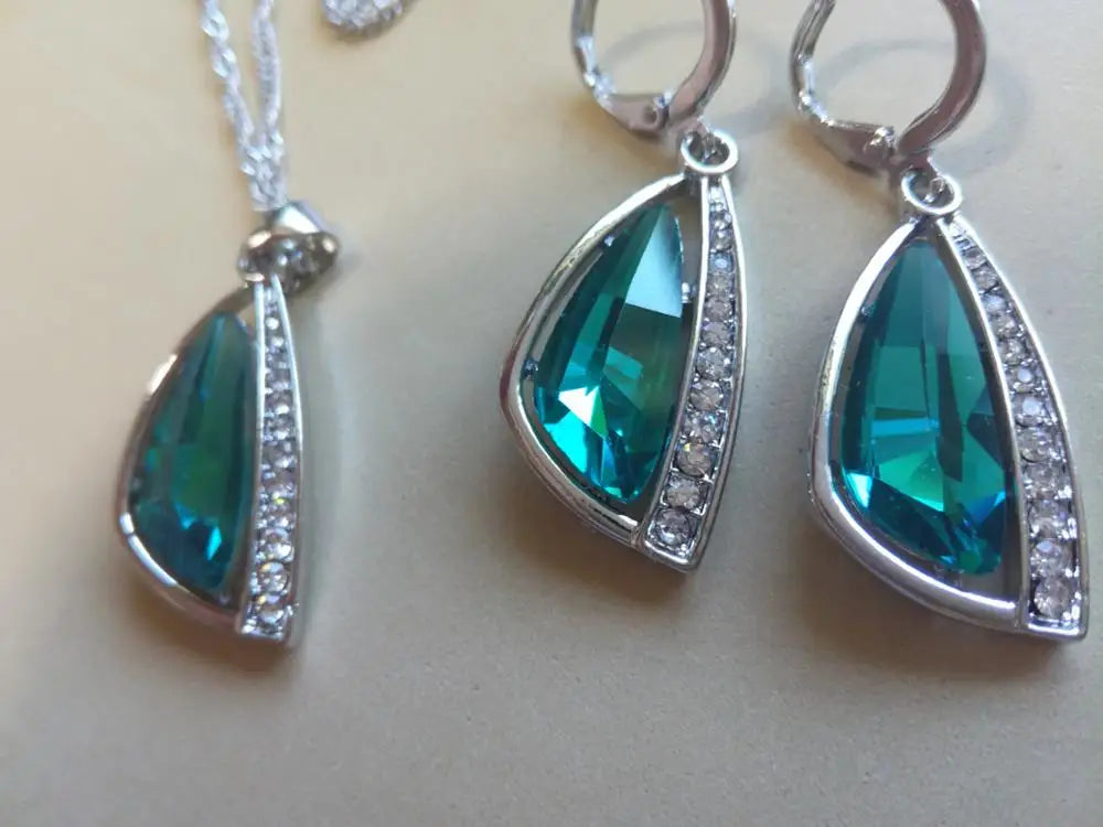 Jewelry set with teal stones and silver accents on a black background, featuring the brand 'Giemi'.