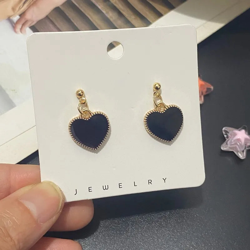 Heart-shaped earrings on a jewelry card held by a hand.