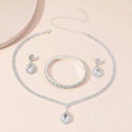 Silver jewelry set with necklace, bracelet, and earrings on a light pink background