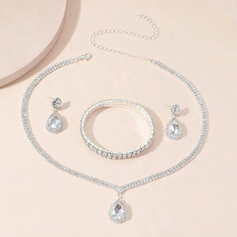 Silver jewelry set with necklace, bracelet, and earrings on a light pink background